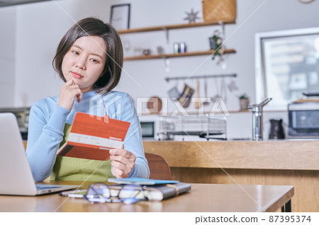 一個穿著圍裙的年輕女人看著她的存摺，想著她的晚年 87395374