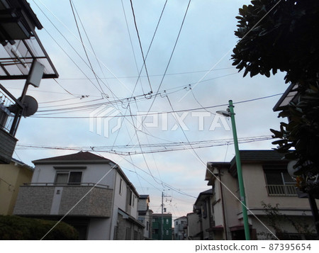抬頭仰望，可以看到橫跨居民區上空的電線和電線桿。 87395654