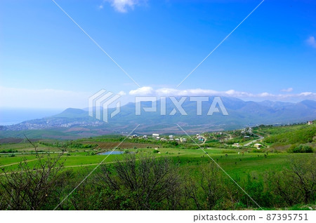 Horizontal background with a magnificent landscape of the Crimean Peninsula. Top view of the mountains covered with lush greenery and the thick clouds below the peaks. Clear blue sky. Copy space. Horizontal background with a magnificent landscape of the Crimean Peninsula. Top view of the mountains covered with lush greenery and the thick clouds below the peaks. Clear blue sky. Copy space. 87395751