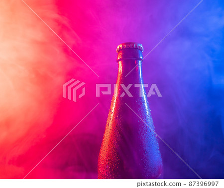 Glass bottle of beer in blue pink mist Glass bottle of beer in blue pink mist 87396997