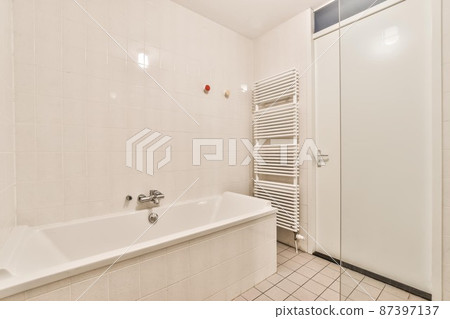 Bathroom in a minimalist style with wall tiles and a large bathtub Bathroom in a minimalist style with wall tiles and a large bathtub 87397137