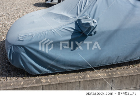A photo of a cover that protects a parked car. Image of car protection and body cover. 87402175