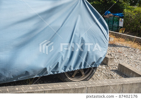 A photo of a cover that protects a parked car. Image of car protection and body cover. 87402176