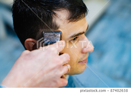 hairdresser makes a haircut of nape for a man with a hair clipper in barbershop hairdresser makes a haircut of nape for a man with a hair clipper in barbershop 87402638
