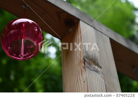 Purple wind chime hanging from a wooden frame 87405228