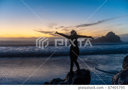 Young woman standing on a rock Young woman standing on a rock 87405795