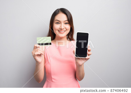 Charming asian woman hand holding smartphone and show credit card. Presenting your product. Charming asian woman hand holding smartphone and show credit card. Presenting your product. 87406492
