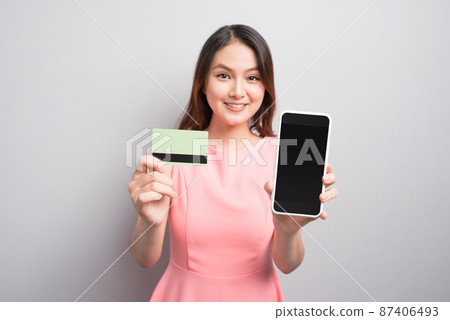 Charming asian woman hand holding smartphone and show credit card. Presenting your product. Charming asian woman hand holding smartphone and show credit card. Presenting your product. 87406493
