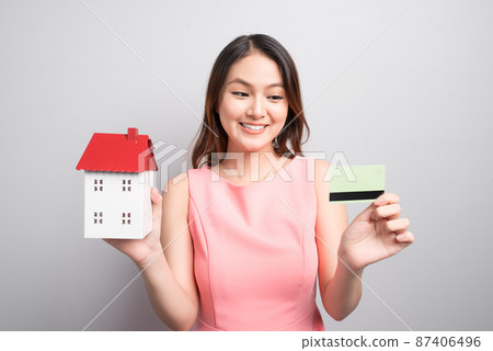 Invest in real estate concept. Woman holding small toy house and credit card in hands Invest in real estate concept. Woman holding small toy house and credit card in hands 87406496