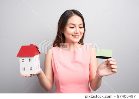 Invest in real estate concept. Woman holding small toy house and credit card in hands 87406497