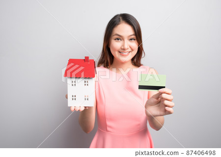 Invest in real estate concept. Woman holding small toy house and credit card in hands 87406498
