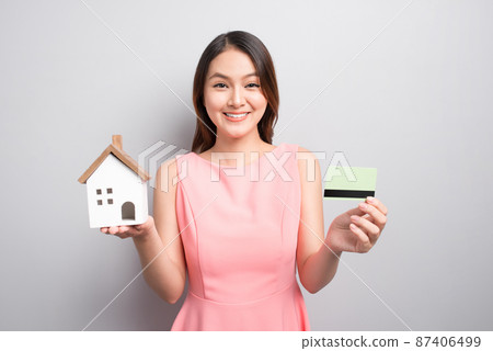 Invest in real estate concept. Woman holding small toy house and credit card in hands Invest in real estate concept. Woman holding small toy house and credit card in hands 87406499