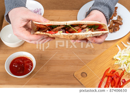 Selective focus on homemade kebab in female hands. Selective focus on homemade kebab in female hands. 87406630