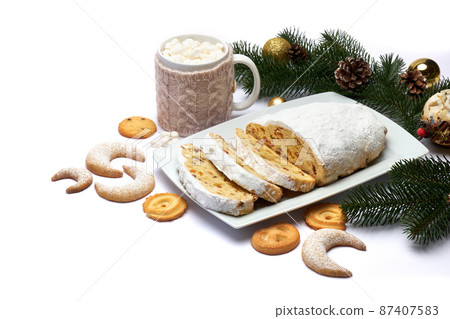 Sliced Traditional Christmas stollen cake with marzipan and dried fruit isolated on ceramic plate 87407583