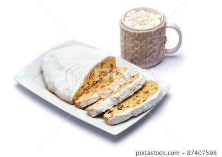 Sliced Traditional Christmas stollen cake with marzipan and dried fruit isolated on ceramic plate Sliced Traditional Christmas stollen cake with marzipan and dried fruit isolated on ceramic plate 87407598