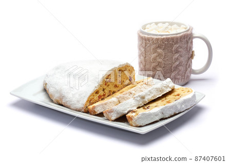 Sliced Traditional Christmas stollen cake with marzipan and dried fruit isolated on ceramic plate Sliced Traditional Christmas stollen cake with marzipan and dried fruit isolated on ceramic plate 87407601