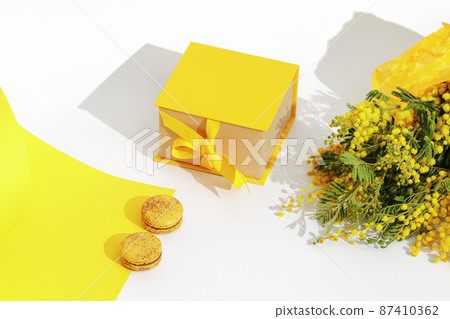 Branches of yellow mimosa flowers, french yellow macaroons and yellow gift box with ribbon bow. Greeting for International Womens Day on March 8, mothers day, Easter, Birthday or spring concept. Branches of yellow mimosa flowers, french yellow macaroons and yellow gift box with ribbon bow. Greeting for International Womens Day on March 8, mothers day, Easter, Birthday or spring concept. 87410362
