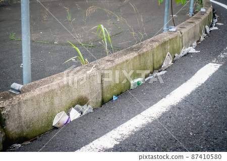 A photo of garbage accumulated on the edge of the road. Image of environmental problems. A photo of garbage accumulated on the edge of the road. Image of environmental problems. 87410580