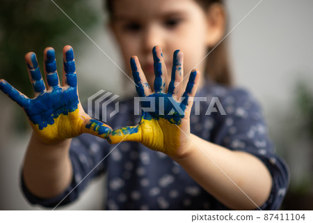 Little girl with hands in paints Ukrainian flag symbolic 87411104