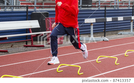 High school sprinter running over six inch mini hurdles on a track 87413357