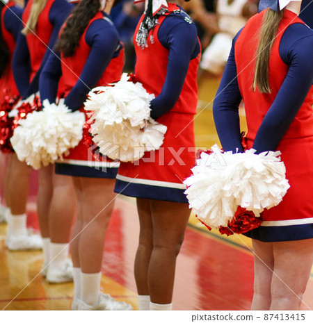 Cheerleaders with pom poms behind them during a basketball game Cheerleaders with pom poms behind them during a basketball game 87413415