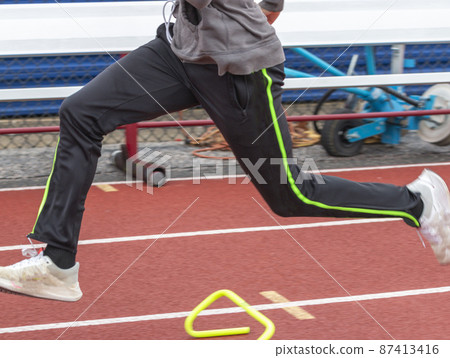 Sprint runner runninng over six inch hurdles on a track 87413416