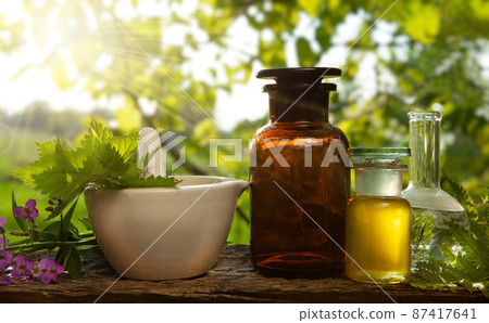 Tincture bottles or mixtures and healthy herbs, a handful of medicinal herbs in a mortar. 87417641