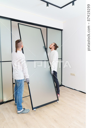 masters install sliding doors of wardrobe made of metal and glass. masters install sliding doors of wardrobe made of metal and glass. 87419299