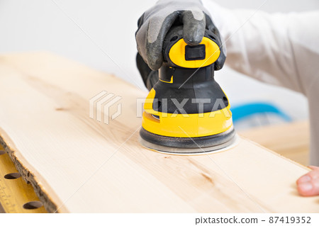 hand of carpenter in protective gloves for working on wood grinding machine hand of carpenter in protective gloves for working on wood grinding machine 87419352
