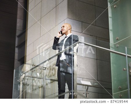 latino business executive talking on cellphone on top of stairs latino business executive talking on cellphone on top of stairs 87419544