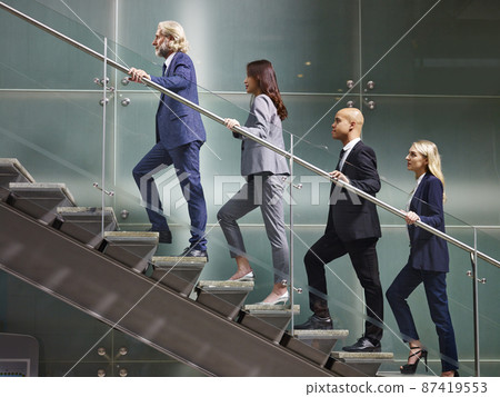 multinational and multiethnic corporate business people walking up stairs in a line 87419553