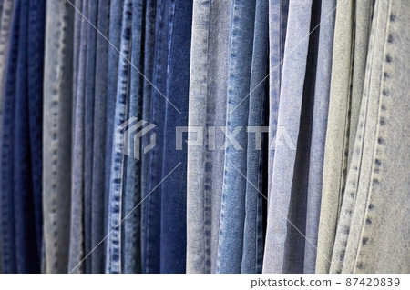 Various blue Jeans on a hanging rack in the clothes store. Close-up, selective focus Various blue Jeans on a hanging rack in the clothes store. Close-up, selective focus 87420839