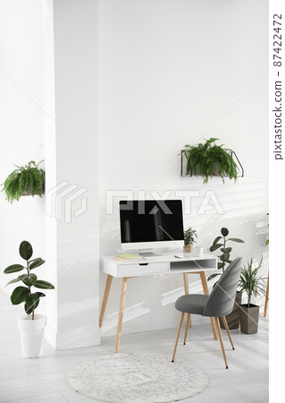 Modern workplace in room decorated with green potted plants. Home design 87422472