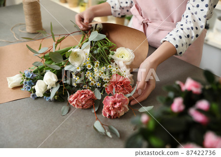 Florist making bouquet with fresh flowers at table, closeup 87422736