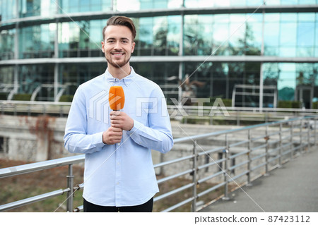 Young male journalist with microphone working on city street. Space for text Young male journalist with microphone working on city street. Space for text 87423112