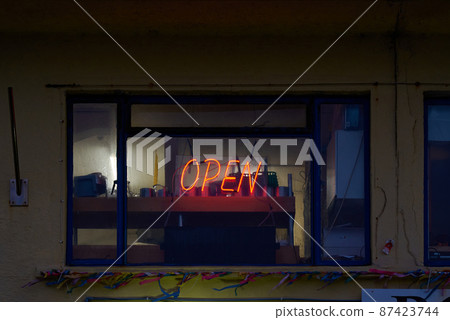 A neon red open sign in a dark shop window A neon red open sign in a dark shop window 87423744
