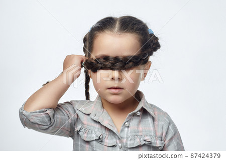 little black-haired girl in fear closed her eyes with her braided pigtail. the concept of child abuse 87424379