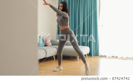 Athletic woman sports workout at home, squats. Home workout. Athletic woman sports workout at home, squats. Home workout. 87424742