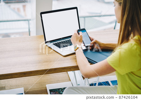 Anonymous female freelancer messaging while working on computer in cafe 87426104