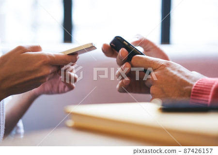 Crop male and female browsing modern smartphones together Crop male and female browsing modern smartphones together 87426157