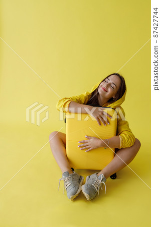 Cheerful young woman hugging travel bag in studio Cheerful young woman hugging travel bag in studio 87427744