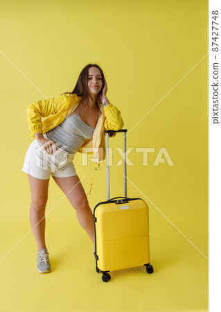 Pretty woman with travel bag standing in studio 87427748