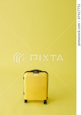 Yellow travel suitcase or trolley luggage bag in studio 87427752