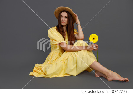 Charming woman with flower sitting on the floor in studio Charming woman with flower sitting on the floor in studio 87427753