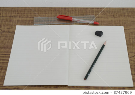 There is a notebook spread out on the desk, and there is a pencil and an eraser. 87427969
