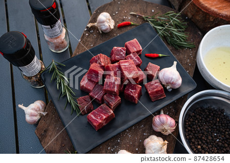 Sliced grilled thai steak served on white plate with grilled sliced lemon, tomatoes, garlic 87428654