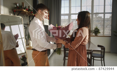 A young man gives flowers to his girlfriend. Romance 87429944