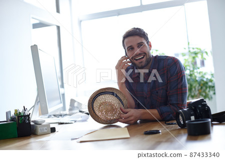 Making my creativity work for me. Shot of a creative professional at his desk talking on his phone. Making my creativity work for me. Shot of a creative professional at his desk talking on his phone. 87433340