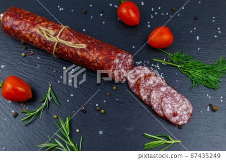 Salami sausage with cherry tomatoes and spices on black slate board. Top view Salami sausage with cherry tomatoes and spices on black slate board. Top view 87435249