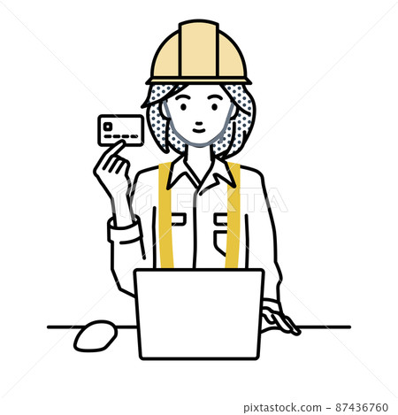 A woman at a construction site sitting at a desk and using a PC while holding a credit card 87436760